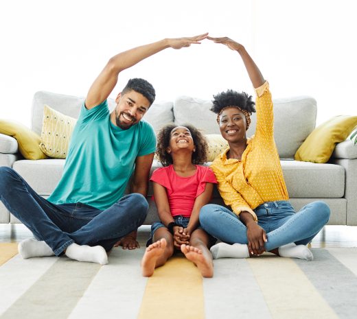 Portrait of a young family forming roof with their hands at new home